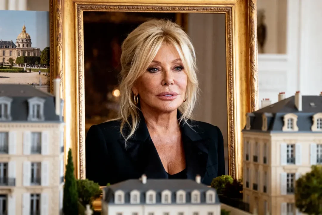 Portrait d'une femme blonde au milieu de miniatures de bâtiments, avec un cadre doré en arrière-plan.
