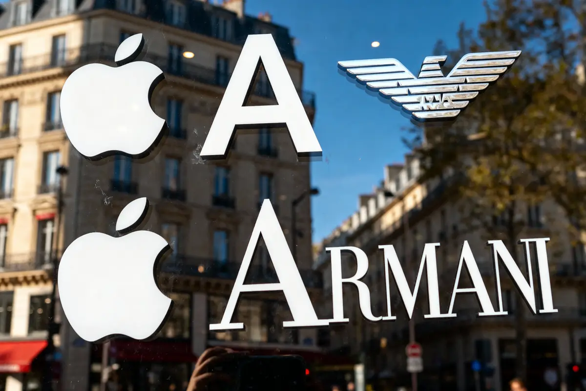 Logos Apple et Armani sur vitrine, reflet de bâtiments en arrière-plan.