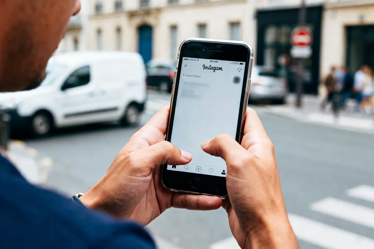 Personne utilisant Instagram sur smartphone pour savoir comment voir qui republie sur Instagram