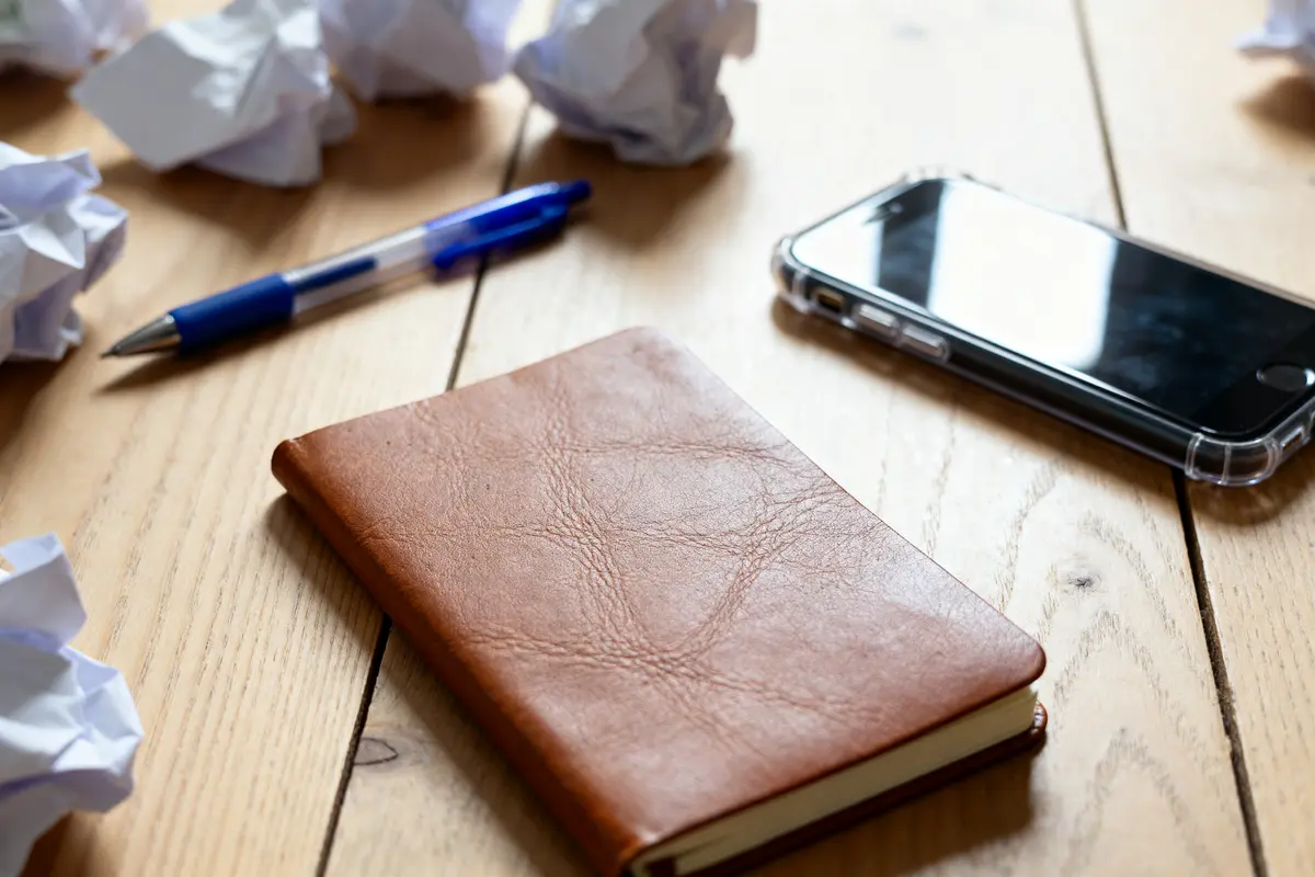Carnet en cuir près d'un téléphone pour gérer un compte à terme 3 mois
