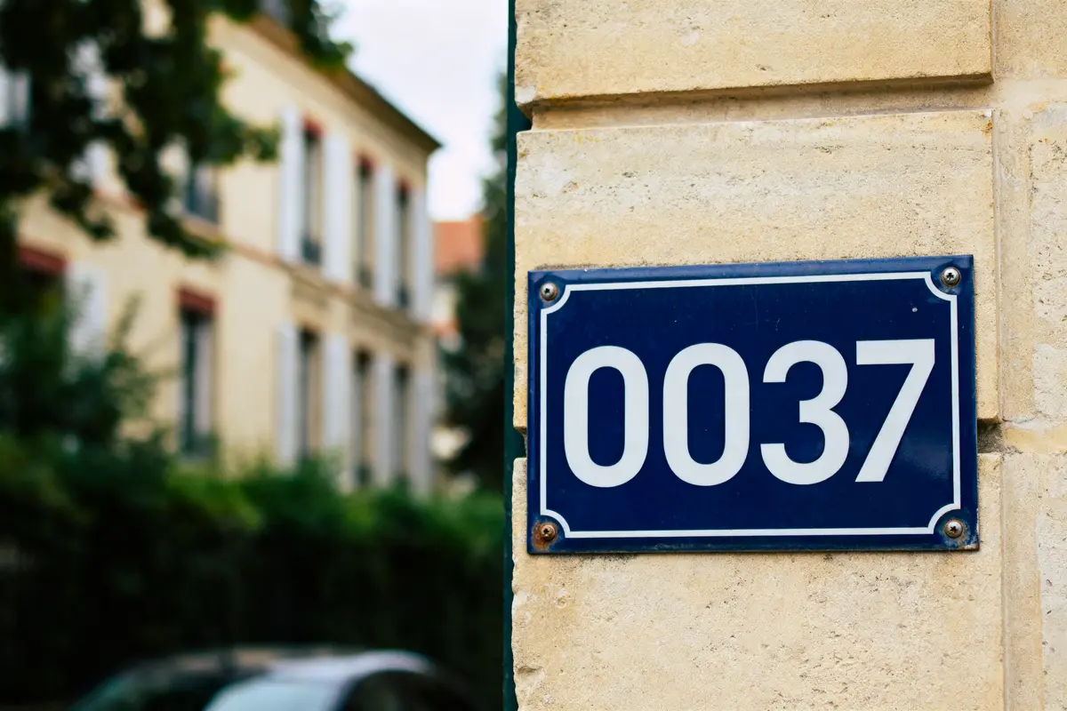 Plaque murale bleue avec le numéro blanc 0037, évoquant oo37 country code bâtiment résidentiel