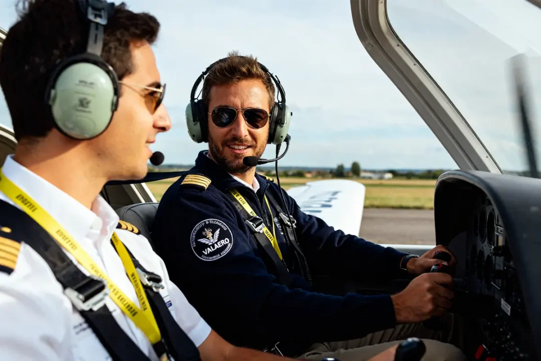 Deux pilotes portant des casques discutent dans un avion valaero sur la piste