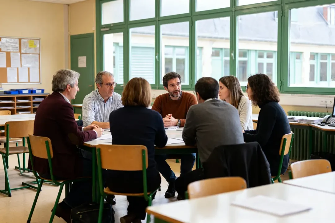 Groupe de personnes en réunion discutant autour d'une table intranet Caen