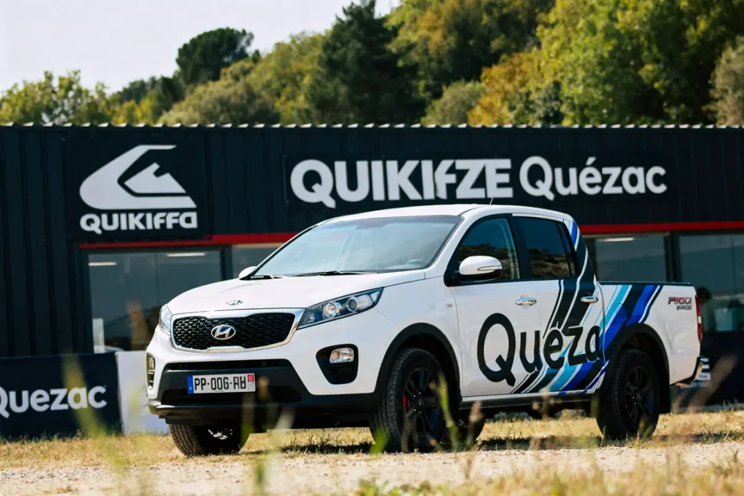 4x4 blanc devant bâtiment Quikiffe Quézac, logo marque en Q visible