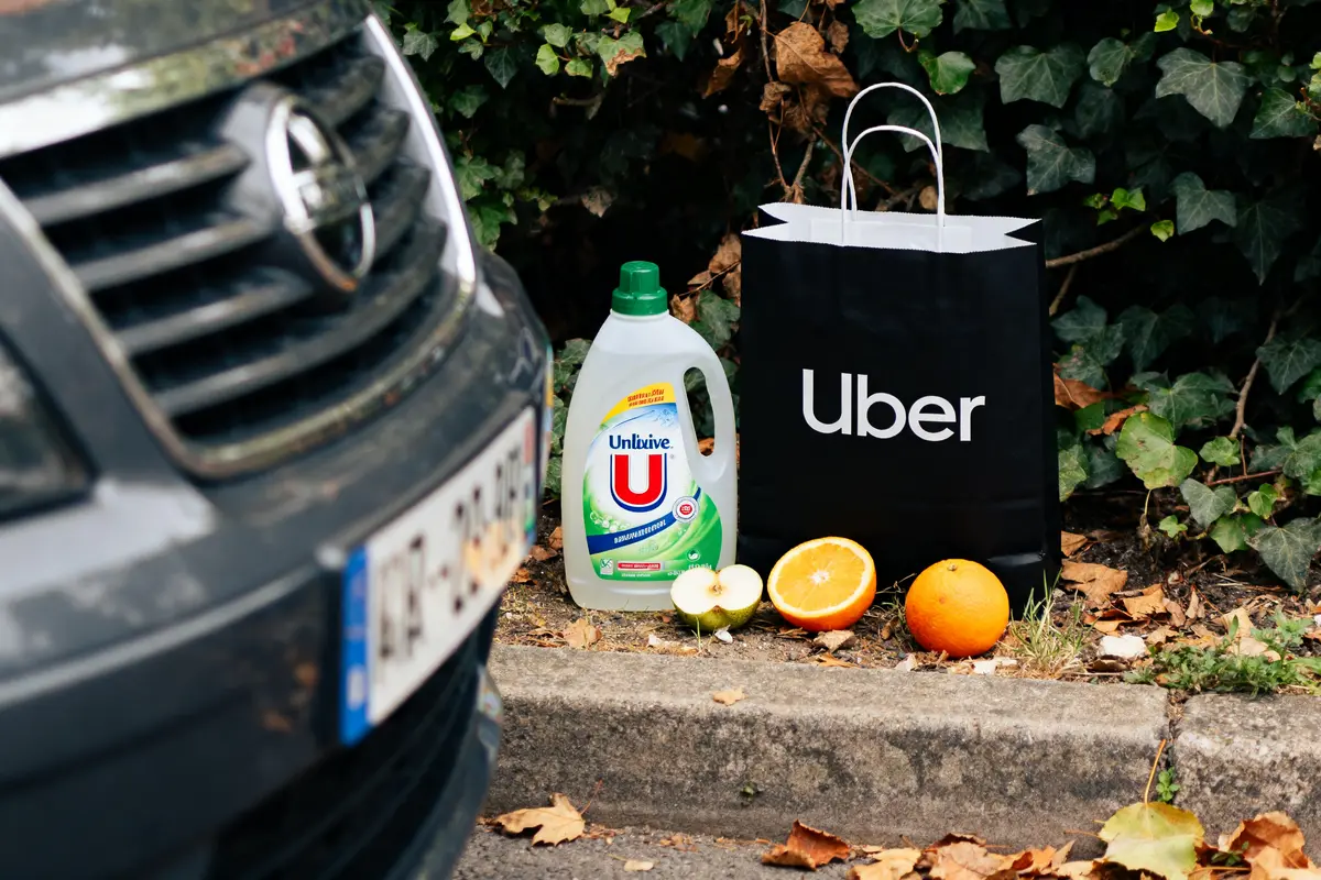 Produits de marque en U avec sac Uber et fruits sur trottoir près d'une voiture