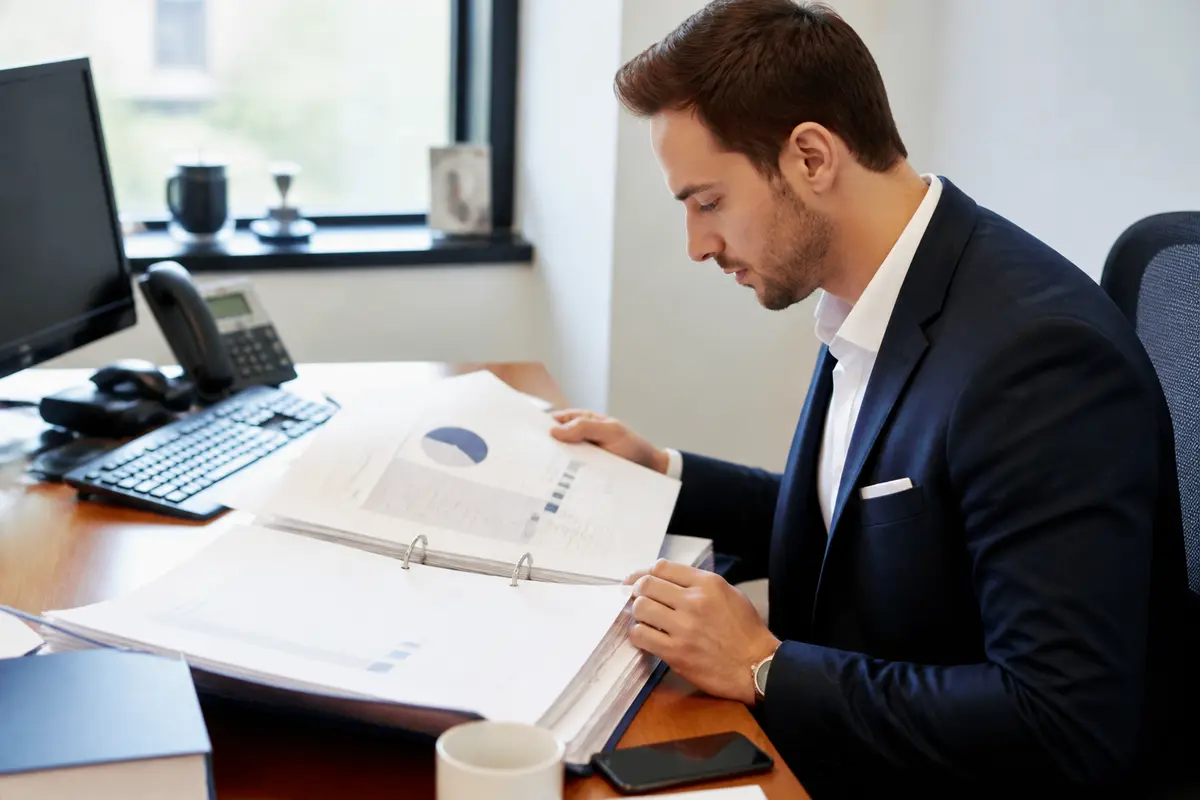 Homme en costume étudiant un dossier sur manuel des lignes commerciales dans un bureau moderne