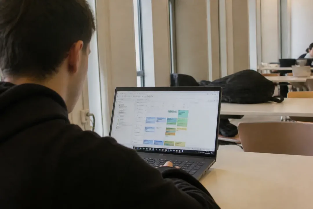 Étudiant utilisant Hyperplanning à Évry sur un ordinateur portable en bibliothèque universitaire