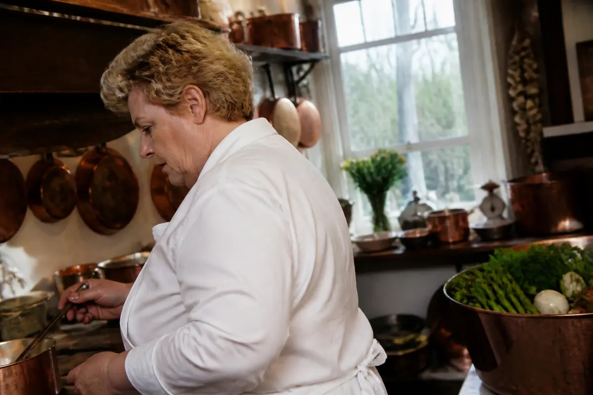 Chef cuisinant dans une cuisine rustique, illustrant la fortune culinaire de Maïté